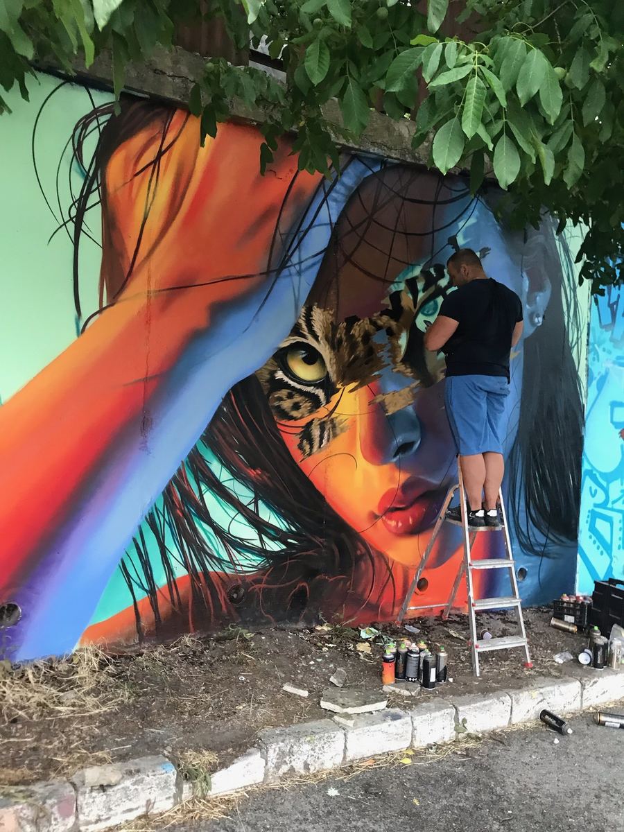 Maliar štúdia na rebríku pri práci na veľkoformátovej nástennej maľbe